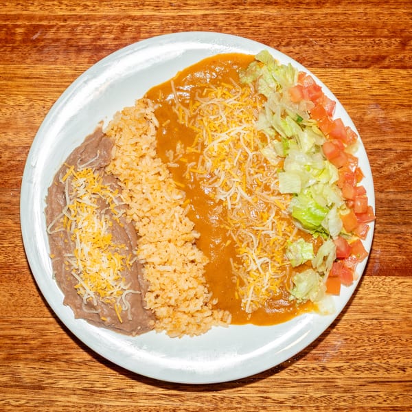 A white plate with refried beans, rice, chili con carne, and a side salad with lettuce and tomatoes.