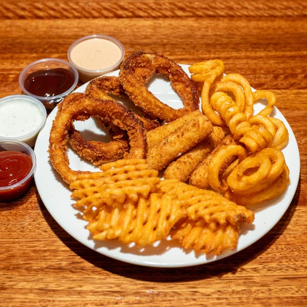 A white plate with fried onion rings, mozzarella sticks, waffle fries, and curly fries, with four dipping sauces.