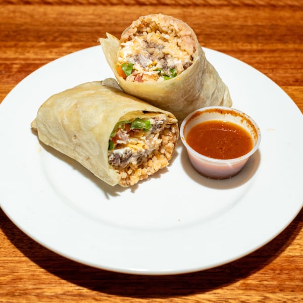 Two burritos, one cut open to show rice, meat, cheese, and vegetables, with a side of salsa.